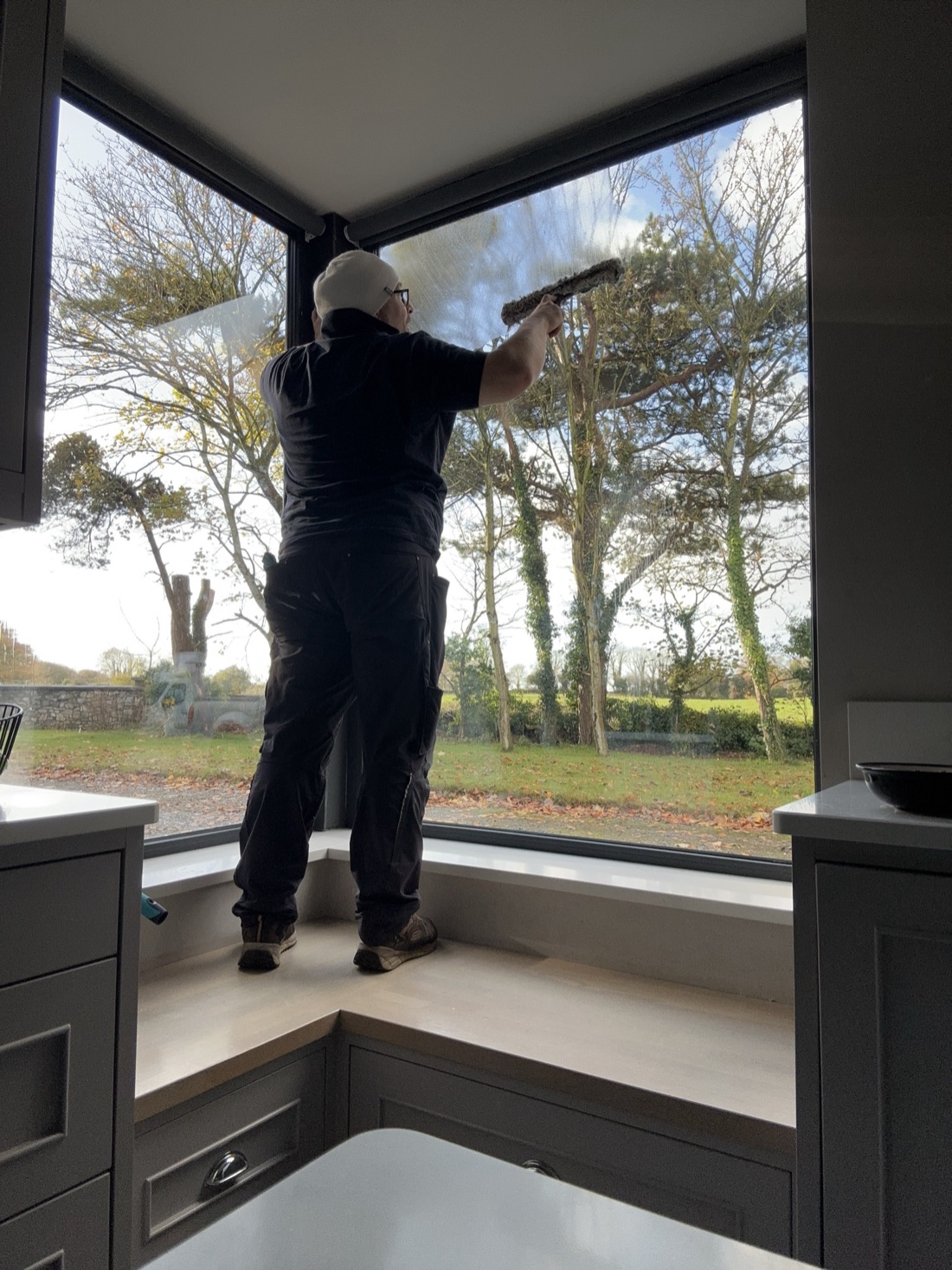 Magic Touch Galway technician cleaning a corner window from inside a kitchen